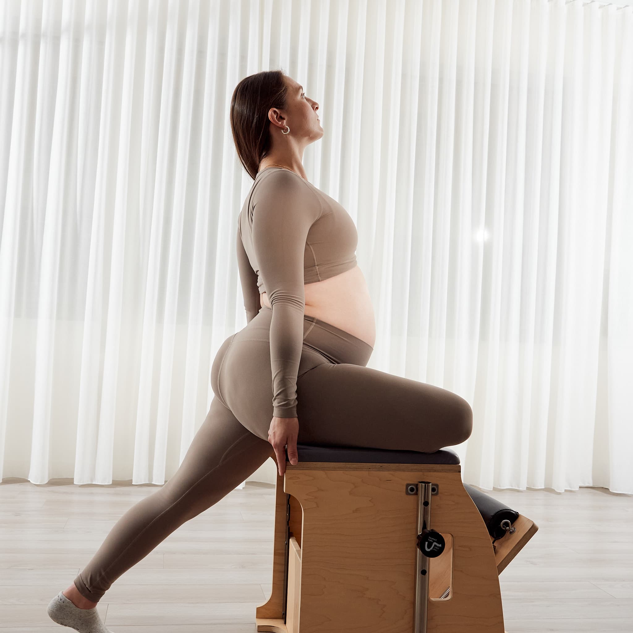 A pregnant client seated on the Wunda Chair with one leg extended behind her
