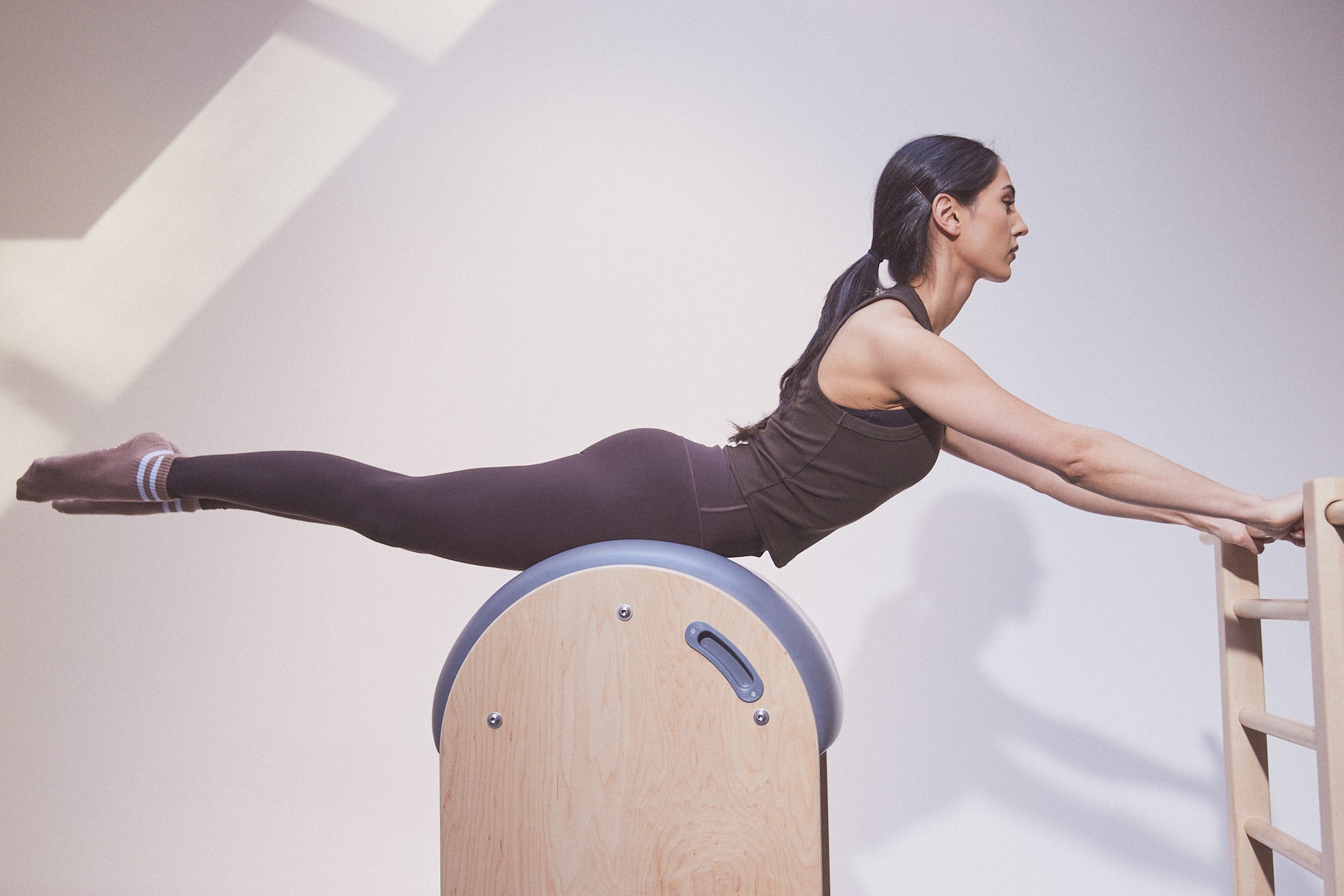 A client extending over the Ladder Barrel at MTLPILATES