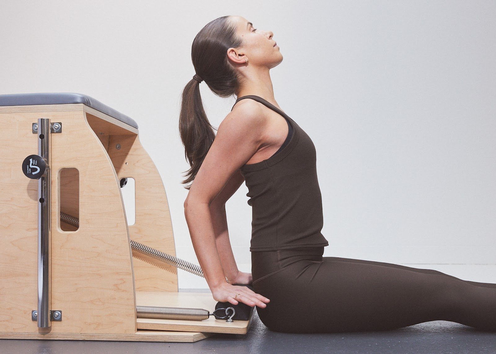 A client sitting tall beside the Wunda Chair, chest lifted and the spine long